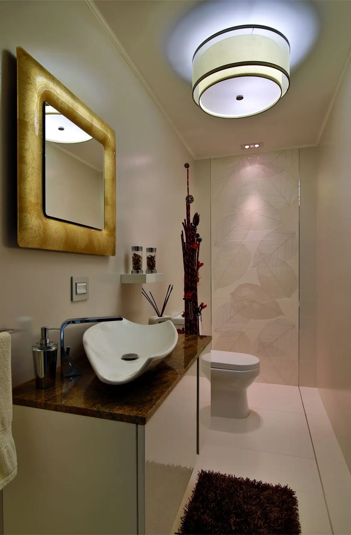 White bathroom with yellow mirror and leaf prints in the wall