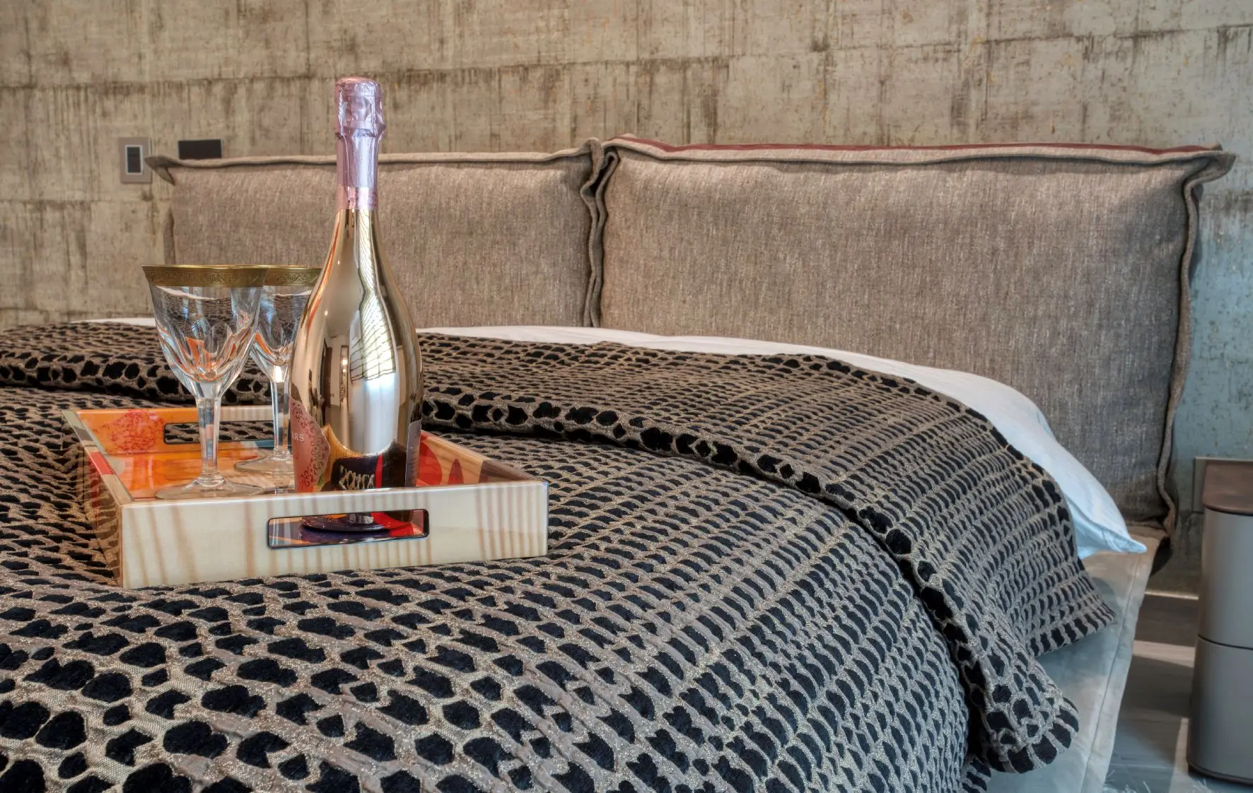 Close shot of bed with bottle and glassware