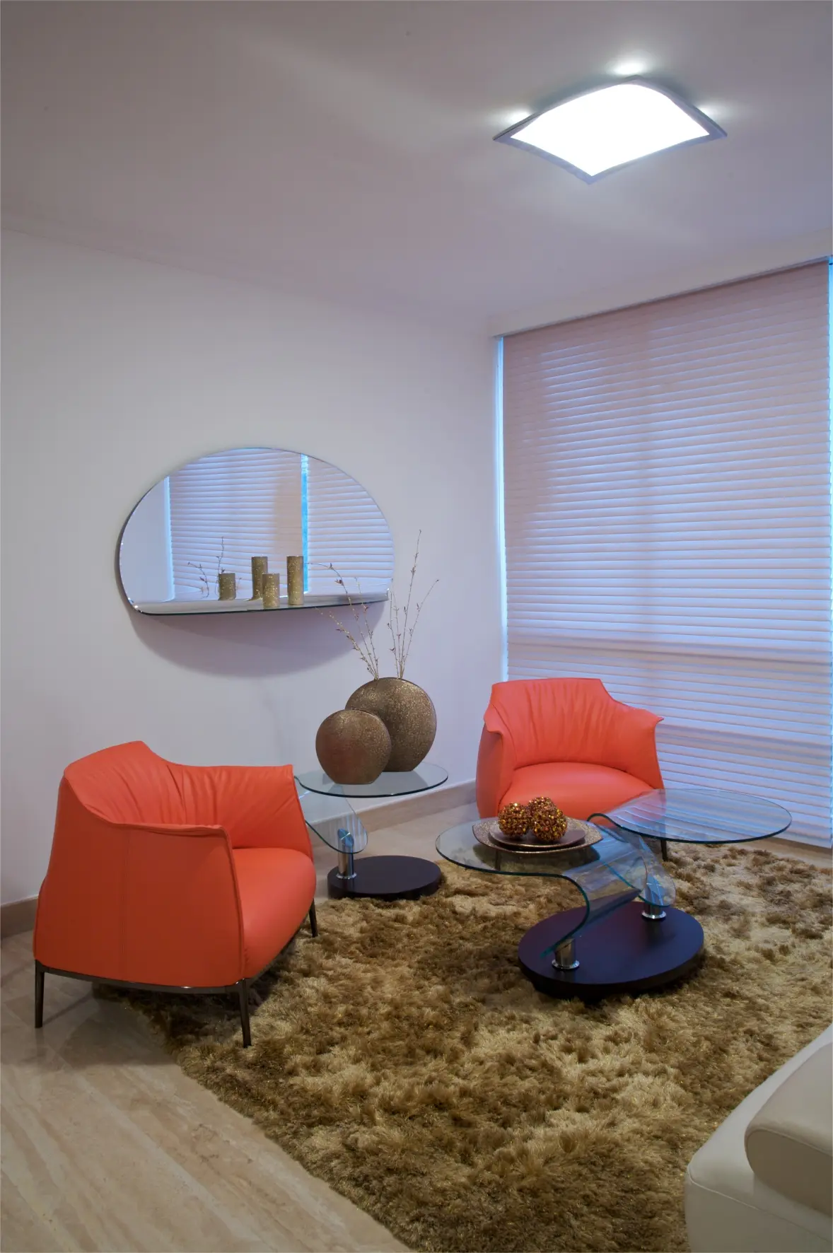 2 orange armchairs with crystal table and mirror and brown carpet
