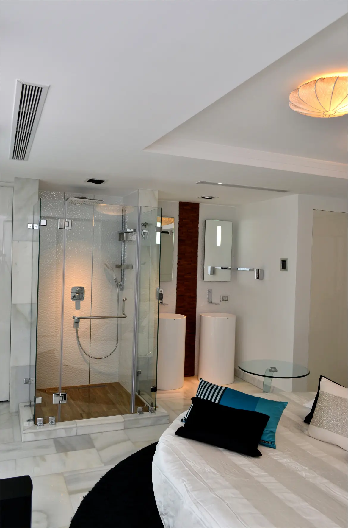 Glass shower besides bed