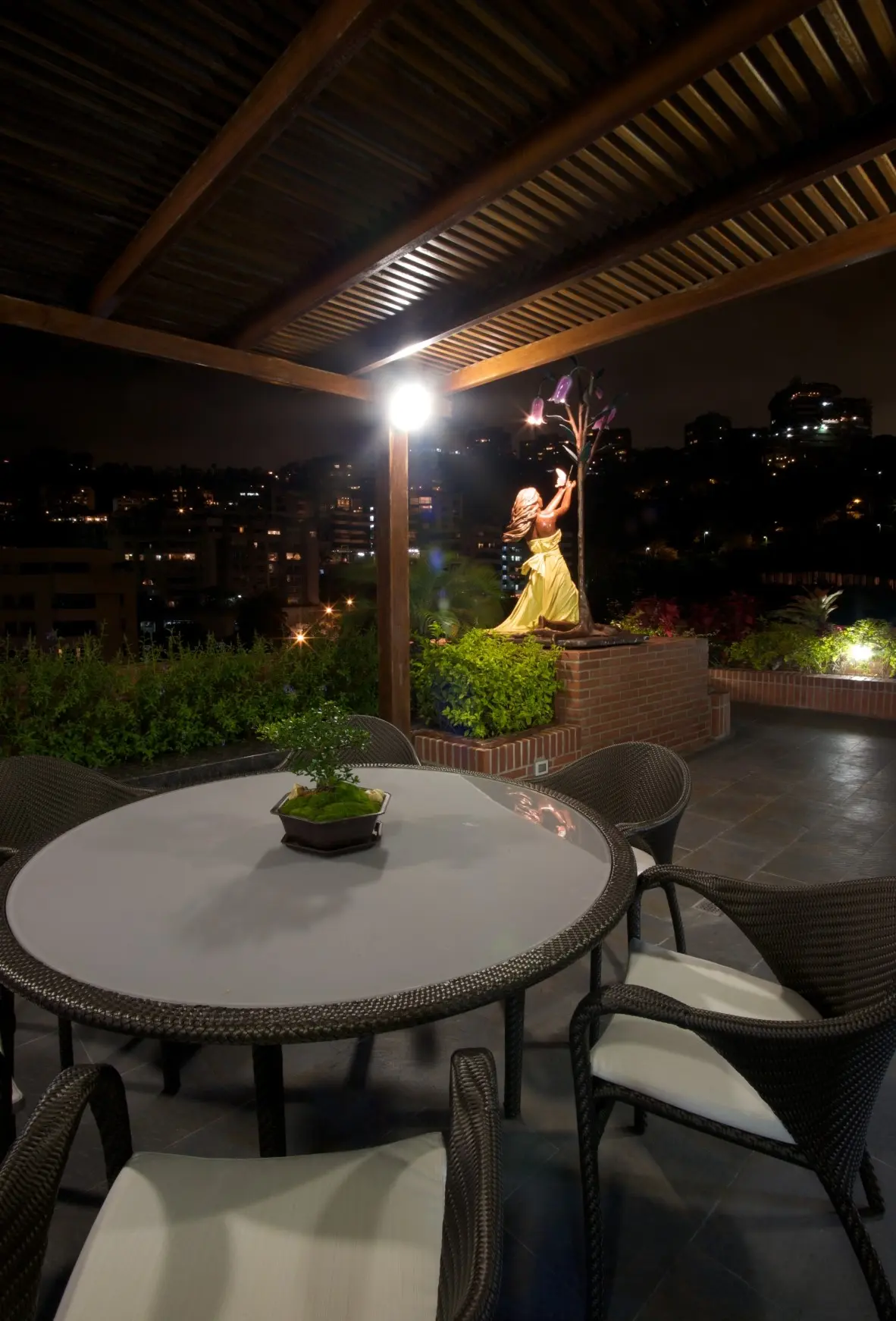 Terrace during the night with white table and sculpture in background