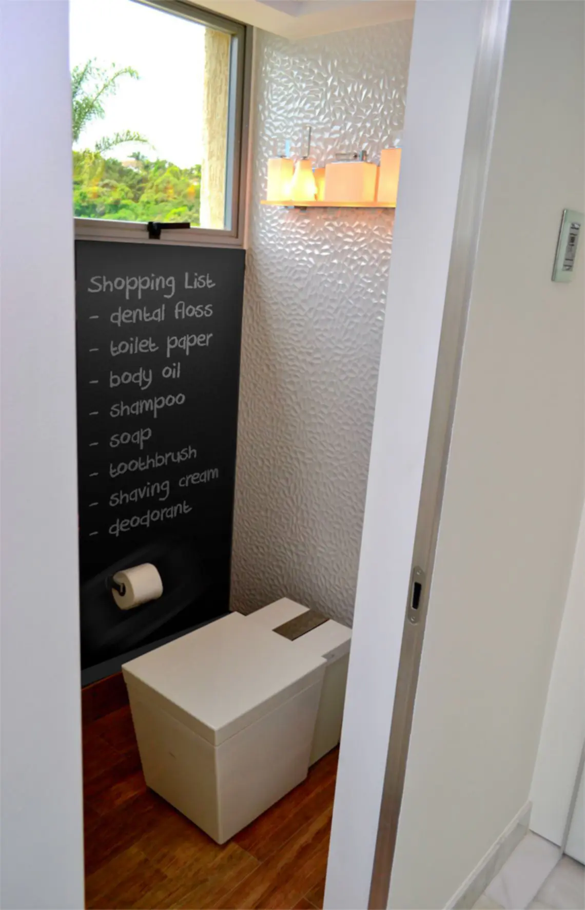 Square toilet with black chalkboard wall and upper window