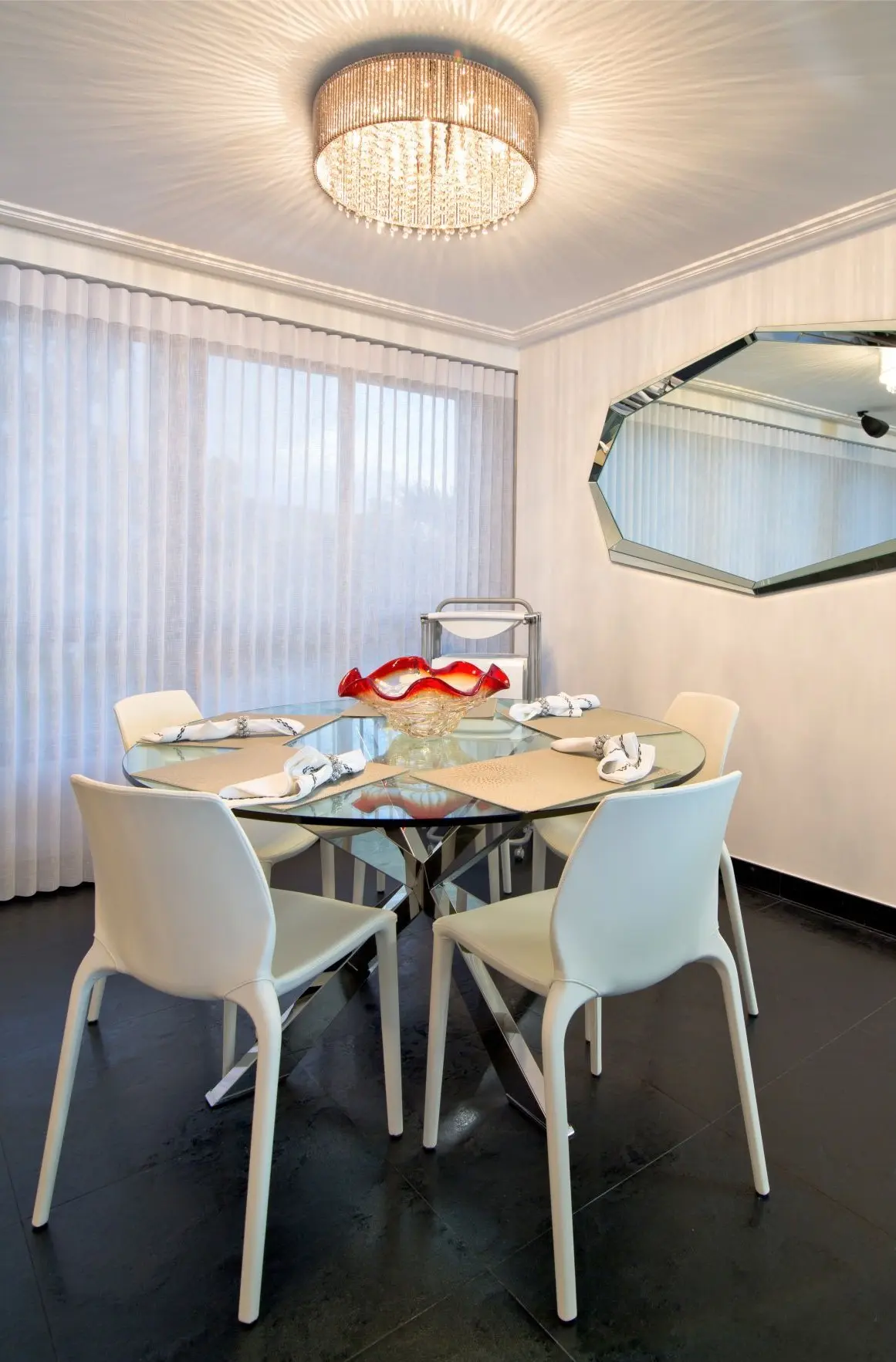 Crystal dining table with white chairs, crystal lamp and octagonal mirror