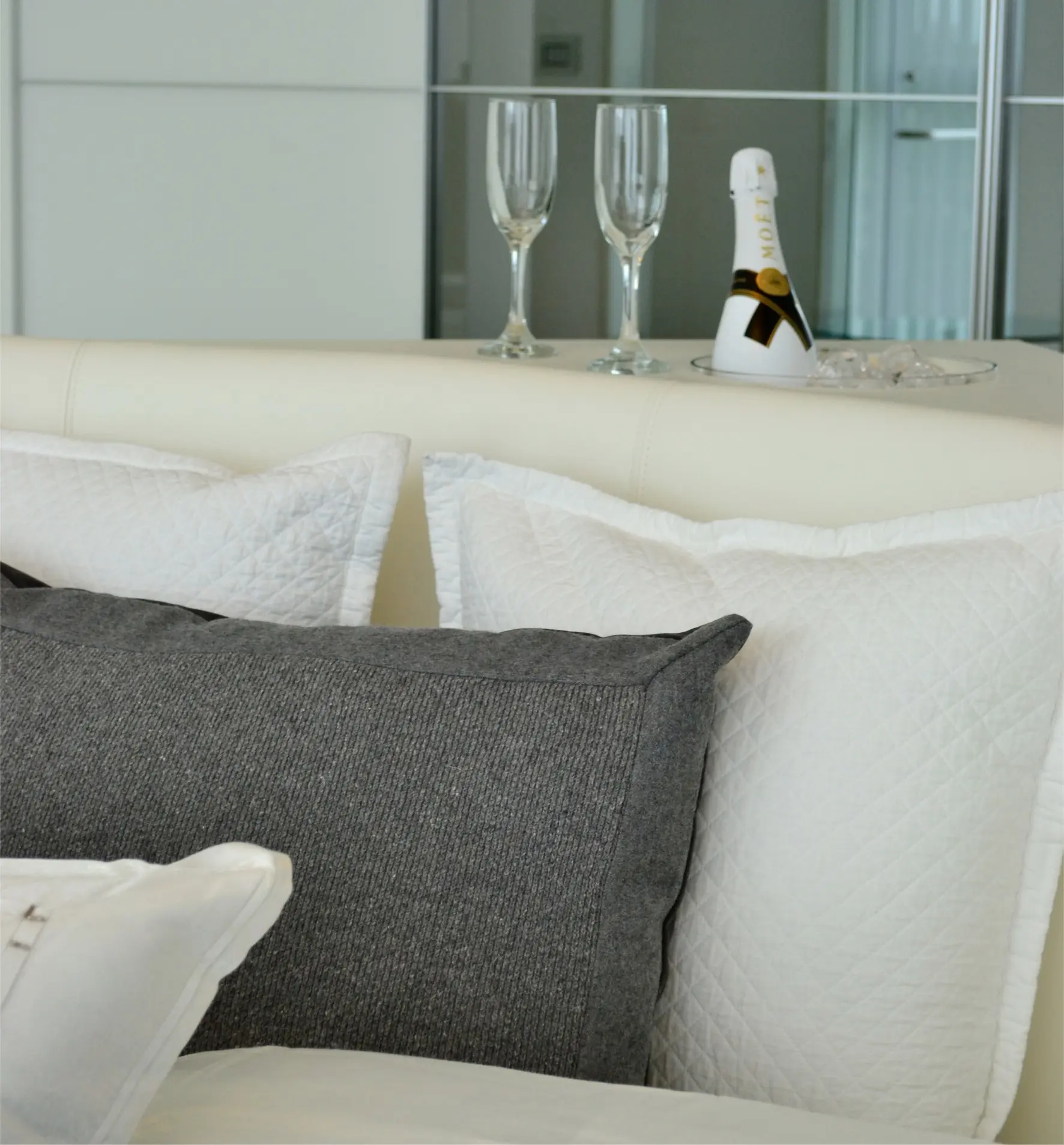 Black and white pillows with bottle and glassware in background