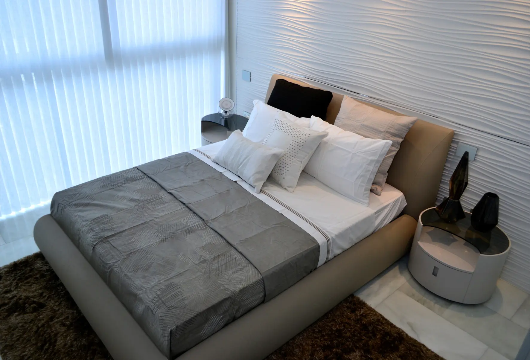 Bed with gray sheets and brown carpet